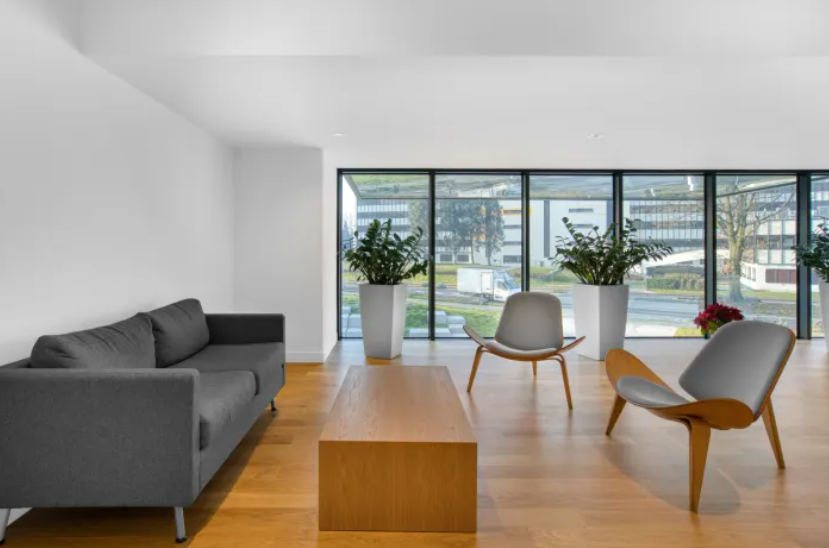 Heller Wartebereich mit Sofa, Tisch, Stühlen und Pflanzen